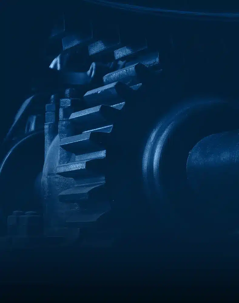 A close-up view of a gear against a dark background, highlighting its intricate details and metallic texture.